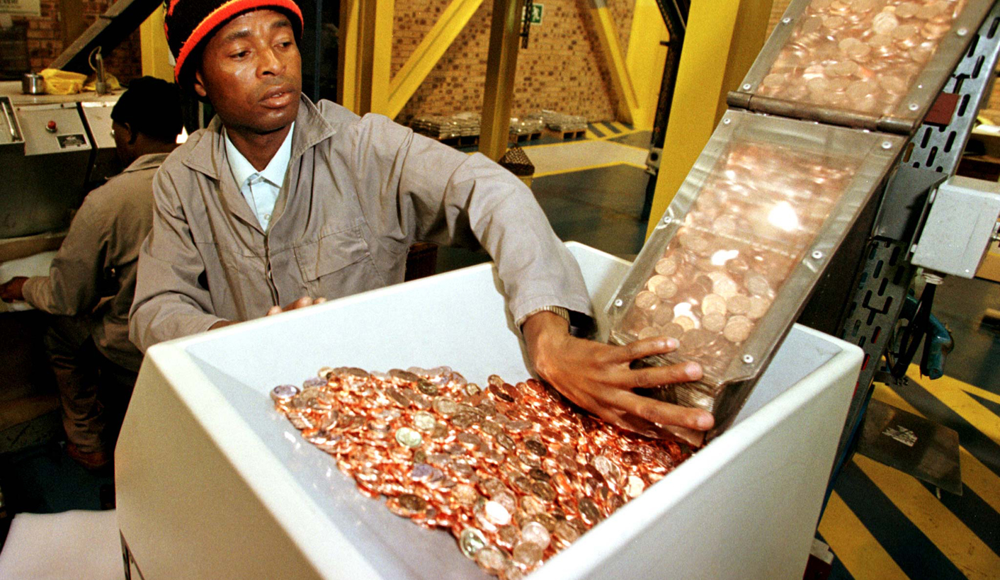 A WORKER AT THE SOUTH AFRICAN MINT INSPECTS RAND COINS.