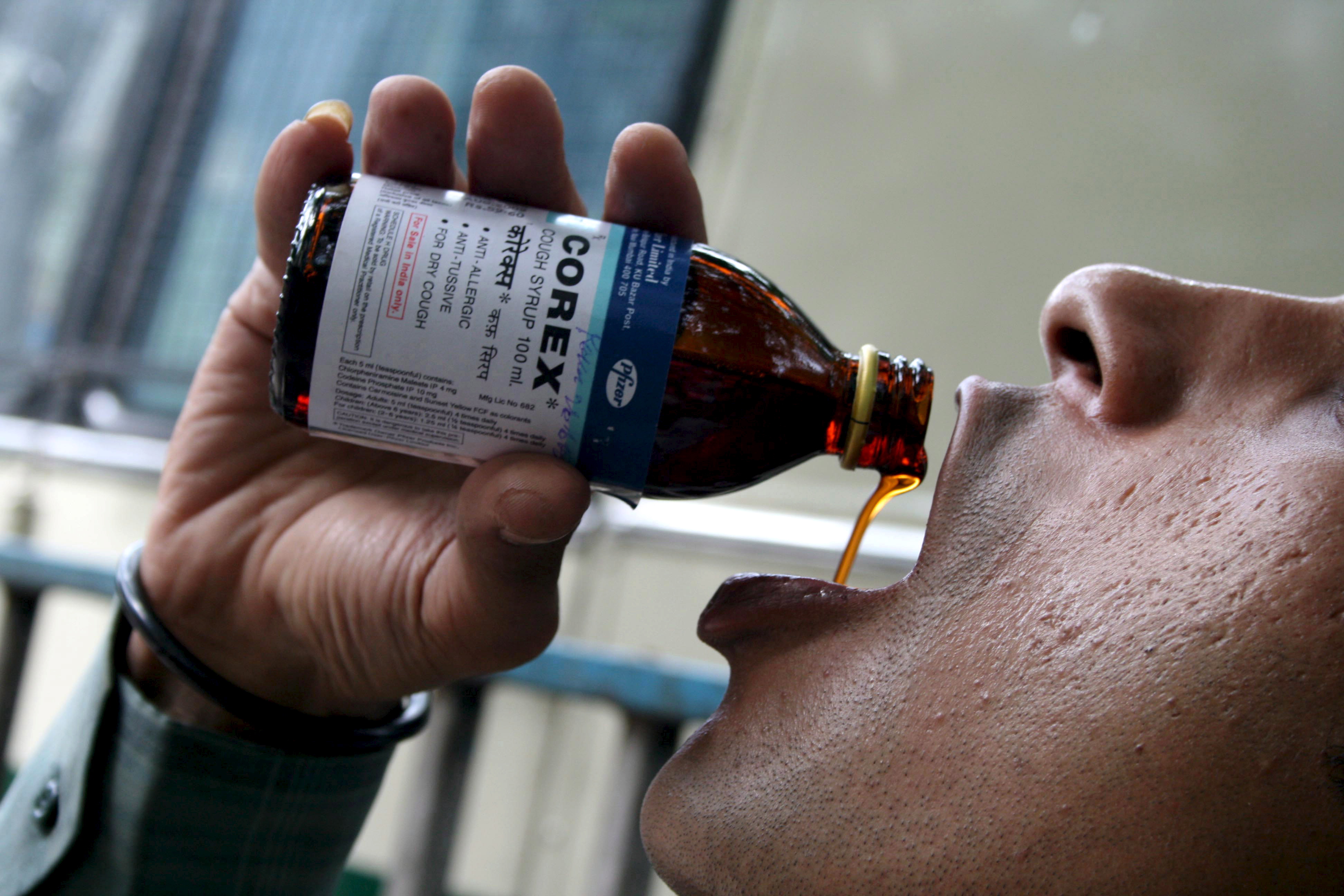 An indian sales man gulps a cough syrup called Corex