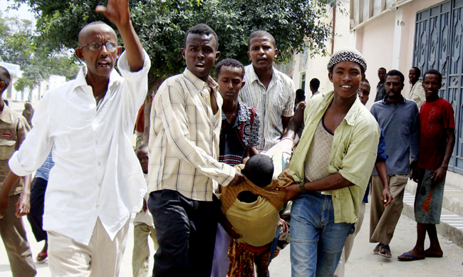 A wounded man is carried by residents after an explosion at the Hotel Shamo in Mogadishu