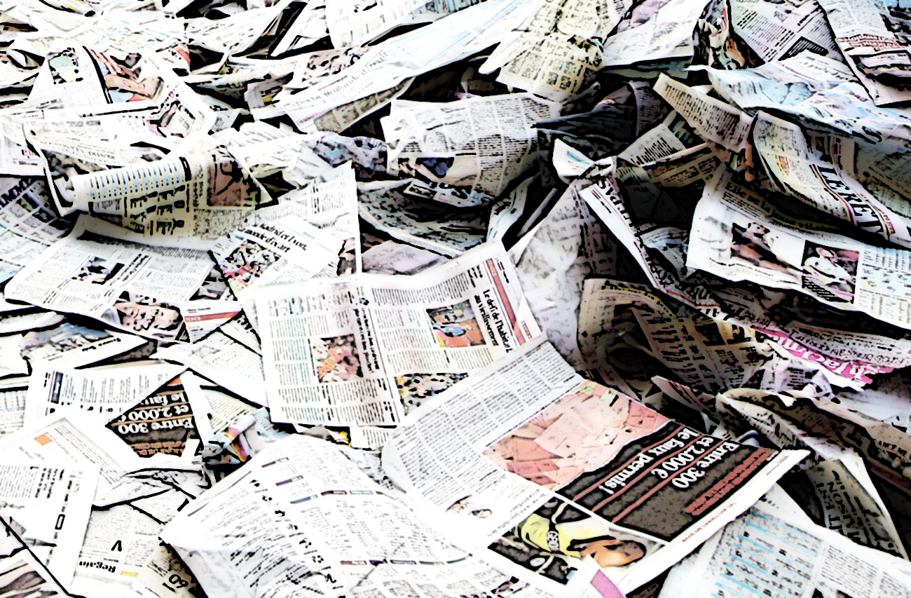 A man rides he bicycle over copies of the French daily 'France Soir' after a union job protest action in Paris