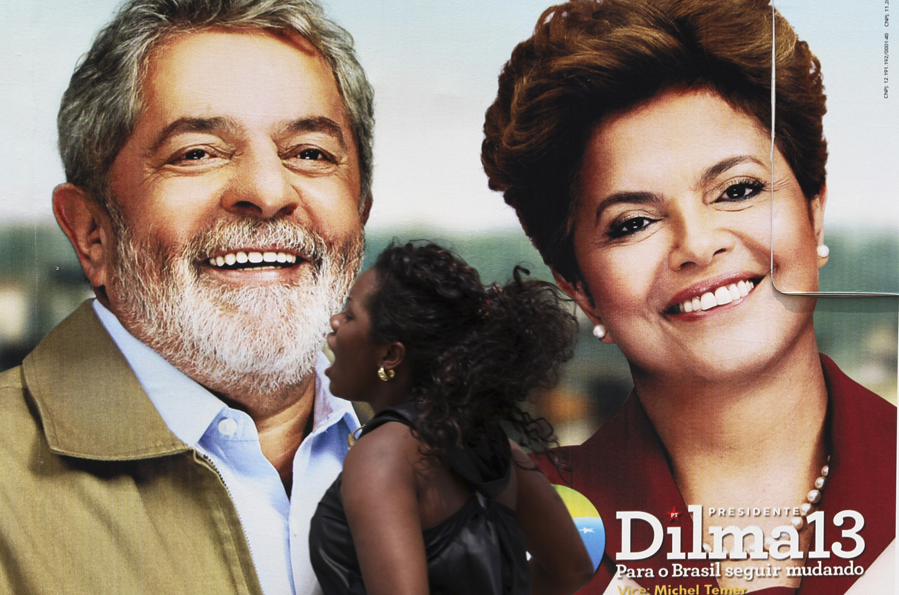 Wman runs in front of Brazil's ruling Workers' Party presidential candidate Rousseff and President Lula da Silva campaing banner during campaign rally in Duque de Caxias