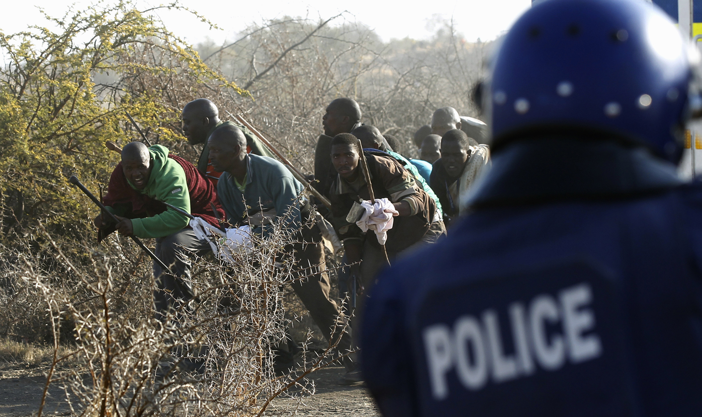 A policeman fires at protesting miners outside a South African mine in Rustenburg