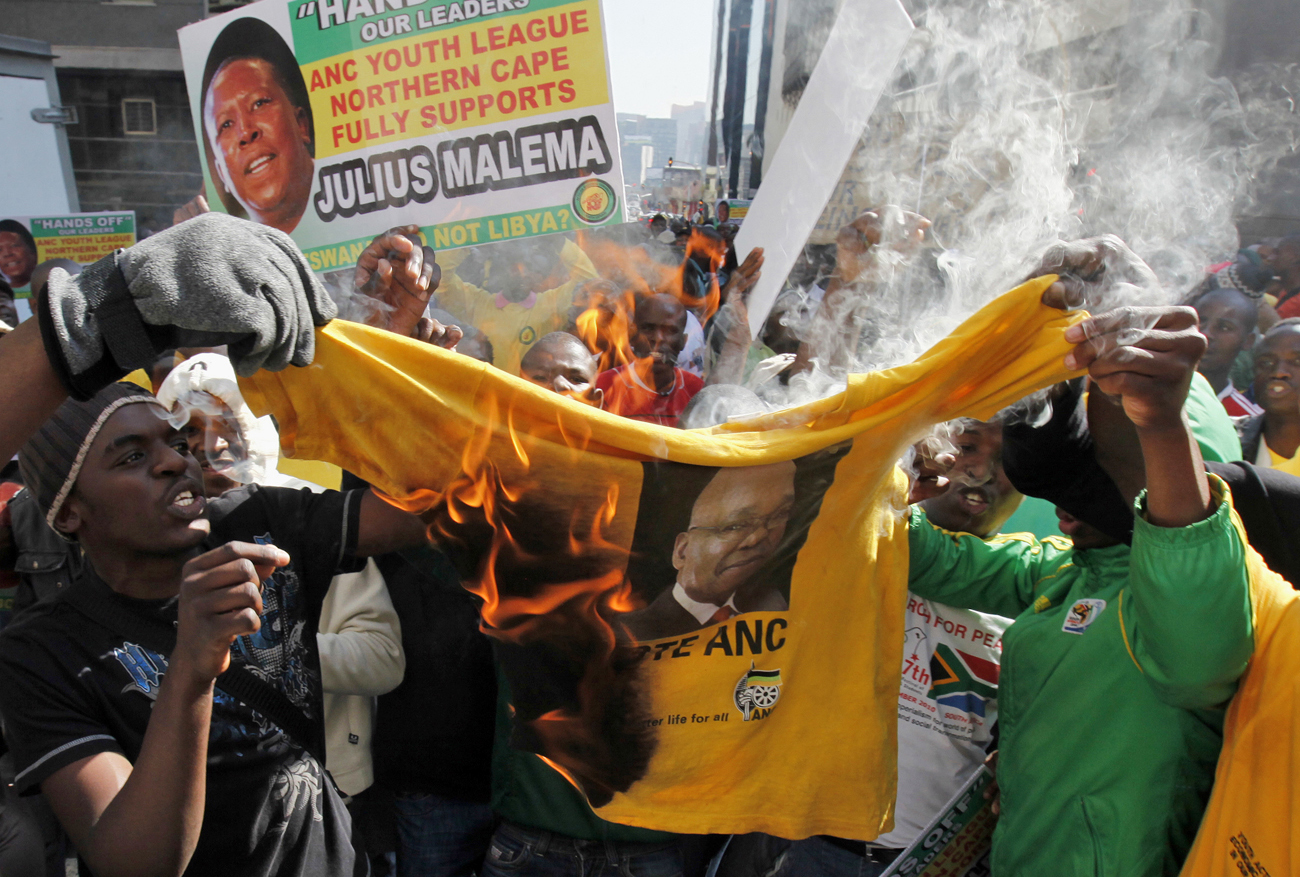 Supporters of ANC Youth League leader Julius Malema burn a shirt bearing the face of South Africa's President Jacob Zuma outside the party headquarters in central Johannesburg