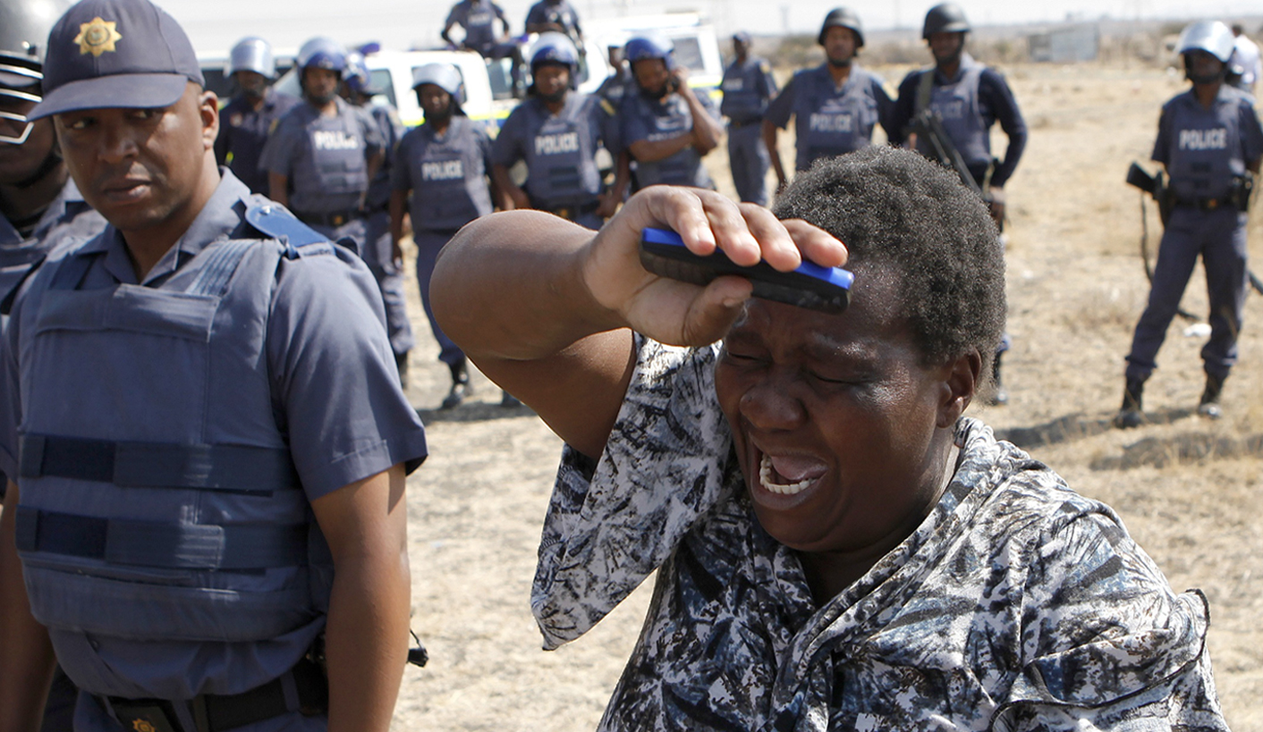 A local women cries as she confronts a police officer during a protest against the killing of miners by South African police on Thursday, outside a South African mine in Rustenburg