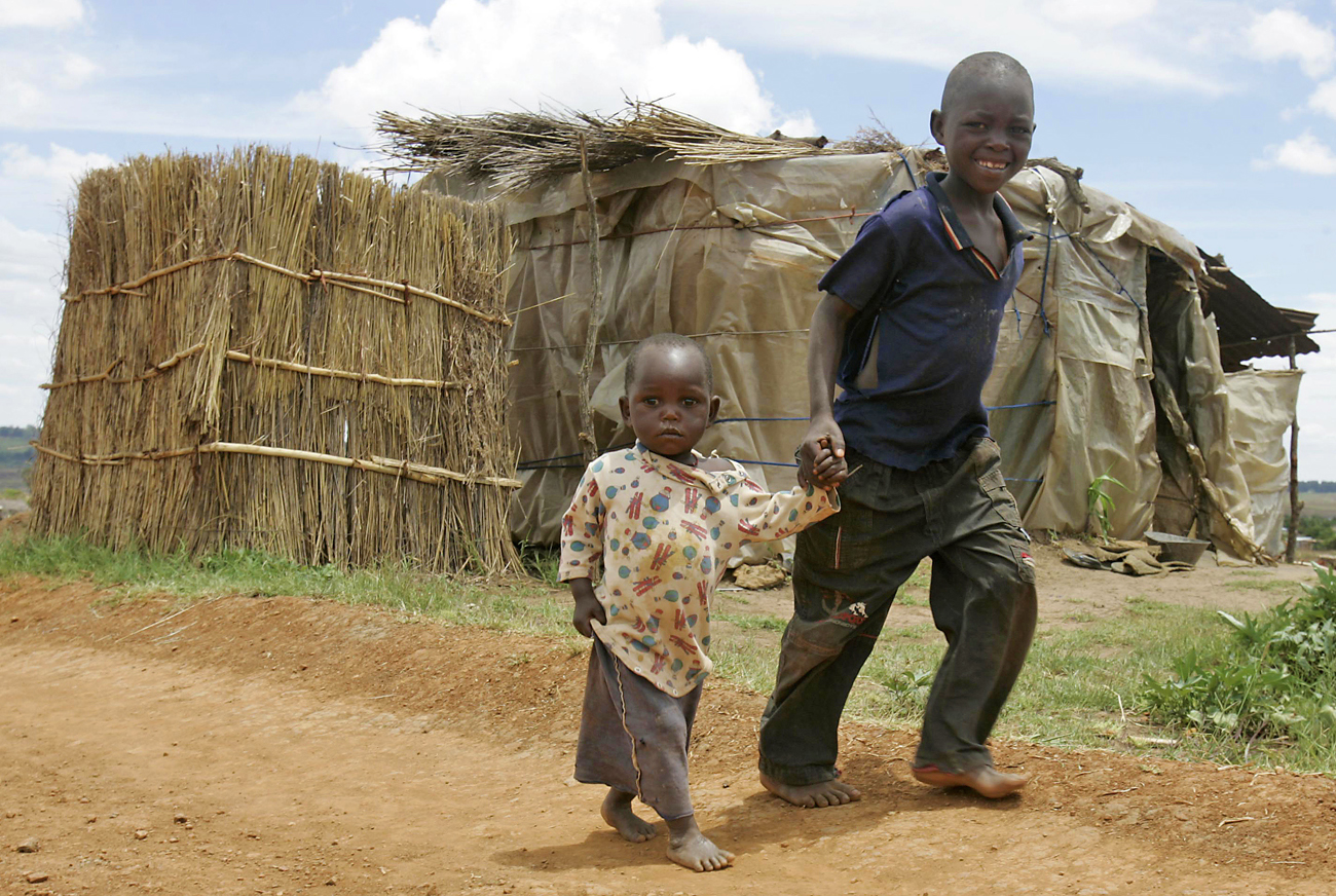 Children walk past makeshift house at slum in Hatcliffe