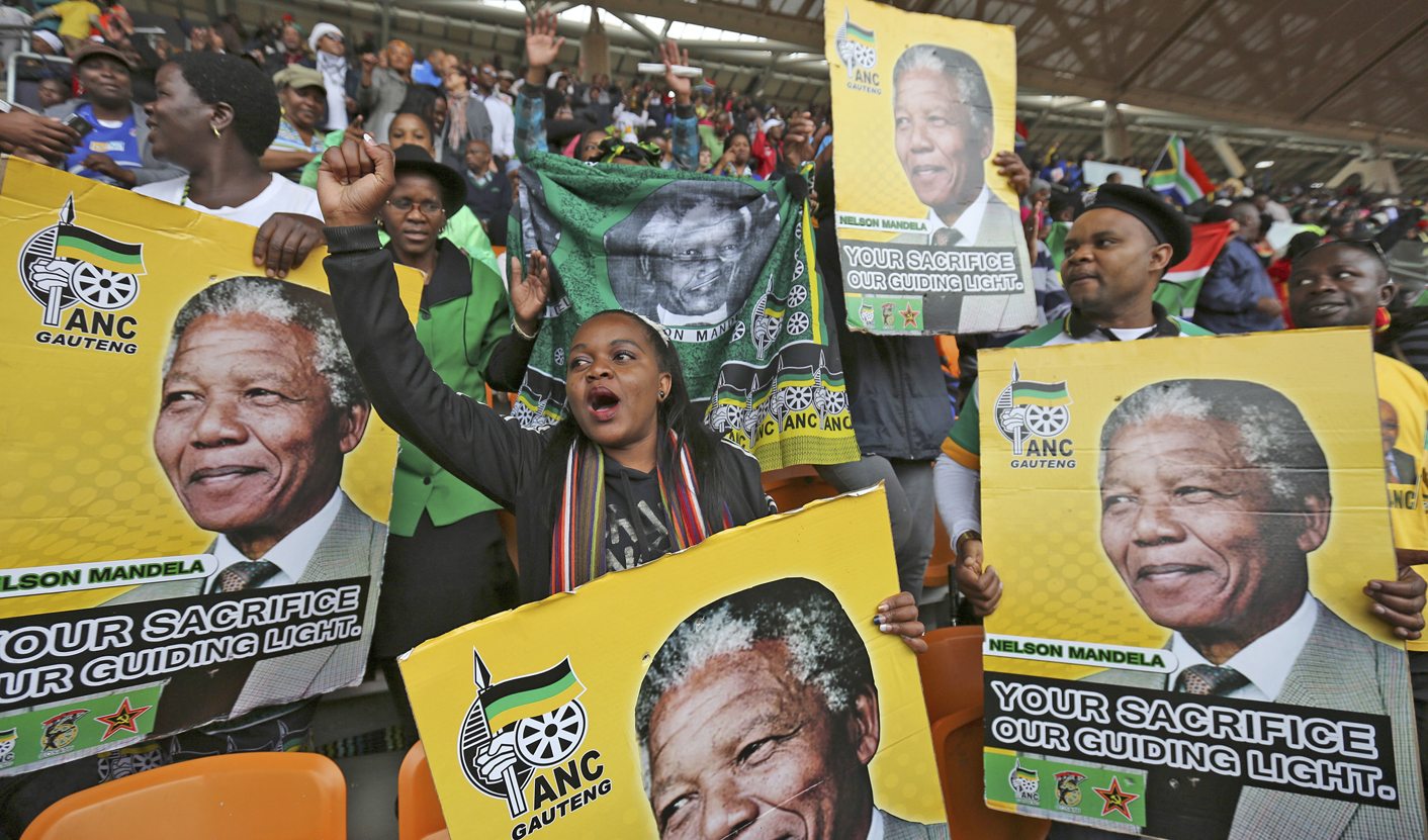 People hold placards of former South African President Mandela at the First National Bank (FNB) Stadium during the national memorial service for Mandela in Johannesburg