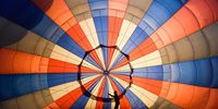 BRISTOL, ENGLAND - AUGUST 04: A person adjusts some lines inside a hot-air balloon before take off on August 04, 2021 in Bristol, England. "Fiesta Fortnight" takes place until Sunday 15th August 2021 with hundreds of hot-air balloons taking off from multiple locations across the city, filling the sky with not only classic hot air balloons, but some special shapes and characters including Stuart the Minion. (Photo by Finnbarr Webster/Getty Images)