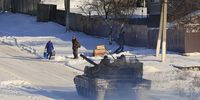 A Ukrainian tank patrols as locals receive humanitarian aid packages delivered by volunteers, in a village near Kupiansk on 19 February 2025. (Photo: Sergey Kozlov / EPA)