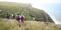 Hikers traverse steep cliffs above the Wild Coast.