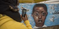 A passerby takes a photo of the mural commemorating teenager Nathaniel Julius who was shot and killed in Eldorado Park. (Photo: Shiraaz Mohamed)