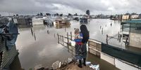 A woman and her baby at a flooded informal settlement in Bloekombos, Kraaifontein, Cape Town on 1 July 2021. (Photo by Gallo Images / Brenton Geach)