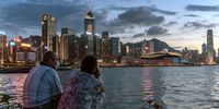 A couple enjoys a moment at a typhoon shelter at sunset in front of the Hong Kong skyline on 30 July 2020. (Photo: Anthony Kwan / Getty Images)