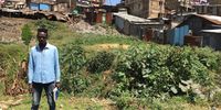 Kevin stands before a building in Mathare.