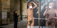 DRESDEN, GERMANY - MAY 05: A visitor wearing a protective face mask stands next to a poster showing Adam and Eve wearing masks as well as indicating a 2 meter distance advise at the entrance to the Zwinger palace complex on the first day the palace reopened to the public during the coronavirus crisis on May 05, 2020 in Dresden, Germany. Museums across Germany are beginning to reopen as authorities continue easing lockdown measures. (Photo by Matthias Rietschel/Getty Images)