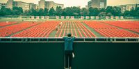 "Ceremony". At a university stadium, a worker is laying a banner for the opening ceremony in two days. He leans over to watch the newly finished stadium. © Shun Wang, China, Shortlist, Open, Street Photography, 2022 Sony World Photography Awards