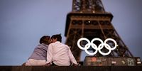 A couple kiss under the Eiffel Tower as the Olympic Rings are displayed during previews ahead of the Paris 2024 Olympic Games on June 27, 2024 in Paris, France. (Photo by Ryan Pierse/Getty Images)