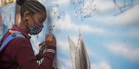 A school pupil writes a message on the mural commemorating Eldorado Park teenager Nathaniel Julius. (Photo: Shiraaz Mohamed)
