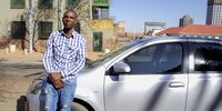 An Uber driver for the past 5 years, Solomon Masala (37) stands alongside his rented vehicle in Braamfontein, Joburg. In the beginning, he says his earnings were good and he enjoyed the flexibility of being a driver. “Now things tend to be a bit sour.” He says that life is tough between high petrol prices, persistently low ride fares, and paying R2500 a week to the vehicle owner.<br>(Photo: Maru Attwood)