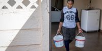 Alice Kunze carries two buckets of water that will be stored for later. 7 September 2022. Lenasia South, Johannesburg. (Photo: Shiraaz Mohamed)