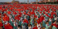 Chinese students wave party and national flags at a ceremony marking the 100th anniversary of the Communist Party at Tiananmen Square on July 1, 2021 in Beijing, China. (Photo by Kevin Frayer/Getty Images)