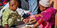 There are 48 children among those displaced by floods in Nelson Mandela Bay over the weekend. Here Liyabana Mpohla shares her friend Aphiwe Ngoza's carrots while they are having lunch. (Photo: Donna van der Watt)