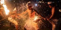 KLUNGKUNG, BALI, INDONESIA - MARCH 02: A Balinese man is hit with burning dried coconut leaves during a fire fight ritual called Lukad Gni as pengerupukan ceremony on March 02, 2022 in Paksebali Village, Klungkung, Bali, Indonesia. The pengerupukan ceremony, held ahead of Nyepi Day celebrations, is a unique ritual in which devotees "fight" each other with fire. The Puri Satria Kawan community believes that the Lukat Gni ritual is conducted to purify the microcosmos (bhuana alit) and macrocosmos (bhuana agung), which is believed to neutralize negative energy and maintain the universe's harmony. (Photo by Agung Parameswara/Getty Images)
