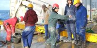 With overalls splattered in mud that could be up to a million years old, scientists take a break from marine core sediment analysis on the deck of the Marion Dufresne. (Photo: Jean-Paul Vanderlinden)