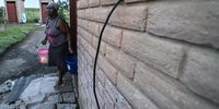 A woman in the Nahamadi Township outside Frankfort carries buckets of water to conduct her chores. Residents complain that they have not had running water for 10 years and have to rely on water provided to them by JoJo tanks.<br>Daily Maverick / Shiraaz Mohamed