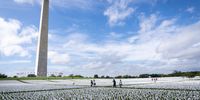 WASHINGTON, DC - SEPTEMBER 21: People walk through 'In America: Remember,' a public art installation commemorating all the Americans who have died due to COVID-19, on the National Mall September 21, 2021 in Washington, DC. The concept of artist Suzanne Brennan Firstenberg, the installation includes more than 660,000 small plastic flags, some with personal messages to those who have died, planted in 20 acres of the National Mall.  (Photo by Drew Angerer/Getty Images)
