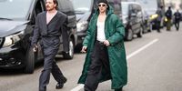 A guest wears a balck wool beanie hat, white sunglasses, a white t-shirt, a green long coat with a hood, black cargo pants, leather shoes, outside K-WAY, during the Milan Fashion Week - Menswear Fall/Winter 2024-2025 on January 14, 2024 in Milan, Italy. (Photo by Edward Berthelot/Getty Images)