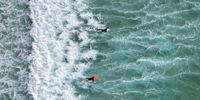 A drone view shows people surfing during spring sunshine, as the warm weather is set to continue into the weekend, at Fistral Beach, Newquay, south west Britain, May 9, 2024. REUTERS/Toby Melville     TPX IMAGES OF THE DAY