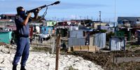 A South African policeman fires tear gas to disperse crowds during a land grab by hundreds in Khayelitsha, Cape Town, South Africa, 21 April 2020. The South African Police and City of Cape Town Metro police used tear gas, stun grenades and rubber bullets to disperse hundreds who had started to mark out plots on the open land and begin building. Residents cite overcrowding and a fear of Covid-19 contamination in the overcrowded informal settlements as the reason for seeking land onto which they wanted to build new shacks. South African is on a total lockdown of the country until the end of April to try stem the spread of the coronavirus SARS-CoV-2 which causes the Covid-19 disease. (Photo:  EPA-EFE/NIC BOTHMA)