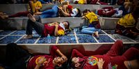 Filipino devotees sleep on bleachers as they wait for the beginning of the procession of the Black Nazarene, during the Feast of the Black Nazarene on January 09, 2024 in Manila, Philippines. The traditional day-long procession of the Feast of the Black Nazarene resumed on January 9, after a three-year hiatus due to COVID-19 precautions. Millions of barefoot devotees participated in the march to see and touch the Black Nazarene, a dark wood sculpture of Jesus brought to the Philippines from Spain in 1606 and considered miraculous by Filipino faithful. (Photo by Ezra Acayan/Getty Images)