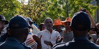Rehad Desai (centre), climate activist and former political exile during apartheid, talks to SAPS officials during a climate protest at Standard Bank HQ, Rosebank. (Julia Evans)