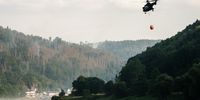 epa10097728 Firefighters operate a helicopter on a forest fire near the village of Bad Schandau, Germany, 29 July 2022. The fire has been raging for days, affecting the border area between the Czech Republic and Germany.  EPA-EFE/CLEMENS BILAN