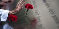 A woman touches a carnation left on a name inscribed into the North Pool during 9/11 Memorial ceremonies marking the 12th anniversary of the 9/11 attacks on the World Trade Center in New York on September 11, 2013 in New York City. The nation is commemorating the anniversary of the 2001 attacks which resulted in the deaths of nearly 3,000 people after two hijacked planes crashed into the World Trade Center, one into the Pentagon in Arlington, Virginia and one crash landed in Shanksville, Pennsylvania. Following the attacks in New York, the former location of the Twin Towers has been turned into the National September 11 Memorial &amp; Museum.  (Photo by Adrees Latif-Pool/Getty Images)
