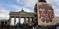 An activist with a banner reading "Climate catastrophe statuesque is child murder" as other  activists of the "Last Generation" ("Letzte Generation") climate action movement, some on bicycles, protest at the Brandenburg Gate under the motto: "Stop the climate collapse. Secure basic rights" on April 23, 2023 in Berlin, Germany. Last Generation has held impromptu protests in Berlin last week and has announced that it will shift to more disruptive protests concentrated in the city center this coming week. The movement's foremost objective is the introduction of a nationwide speed limit as a means to bring down fossil fuel emissions. (Photo by Omer Messinger/Getty Images)