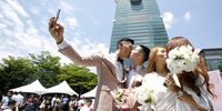 Married couples kiss while posing for photographs in front of the Taipei 101 building during a pro same-sex marriage party organized by the Taipei City government and Marriage Equality Coalition Taiwan in Taipei, Taiwan, on Friday, May 24, 2019. Same-sex couples in Taiwan celebrated as it held the first gay marriages anywhere in Asia on Friday. Photographer: Ashley Pon/Bloomberg via Getty Images