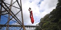 Hector Chacon, of the Municipal Firefighters, wears a Santa Claus costume as he descends from the Las Vacas railway bridge in Guatemala City, Guatemala, 17 December 2023, during a Christmas gift-giving ceremony to low-income children of the Jesus de la Esperanza settlement.  EPA-EFE/EDWIN BERCIAN