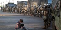 MINNEAPOLIS, MINNESOTA - MAY 29: A women reads a bible in front of a line of National Guardsmen as the 8pm curfew approaches during protests sparked by the death of George Floyd while in police custody on May 29, 2020 in Minneapolis, Minnesota. Earlier today, former Minneapolis police officer Derek Chauvin was taken into custody for Floyd's death. Chauvin has been accused of kneeling on Floyd's neck as he pleaded with him about not being able to breathe. Floyd was pronounced dead a short while later. Chauvin and 3 other officers, who were involved in the arrest, were fired from the police department after a video of the arrest was circulated. (Photo by Scott Olson/Getty Images)