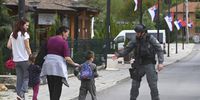 An armed Kosovo Police officer greets a young boy while patroling the village of Banjska, Kosovo, 27 September 2023. A Kosovar Albanian police officer on 24 September was killed by Serb gunmen who later barricaded themself in the XIV century Serbian Orthodox Banjska monastery and traded gunfire for hours, Kosovo authorities confirmed. Police regained control of the area late on the same day. The incident came at a fragile moment in the Kosovo - Serbia European Union-facilitated dialogue to normalize ties between the two parties.  EPA-EFE/GEORGI LICOVSKI