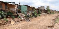 Alexandra resident Helen Tshabalala walks alongside informal houses standing close to the riverbank in Alexandra. (Photo: Felix Dlangamandla)
