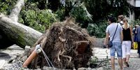 People walk past a felled tree at Castello Sforzesco after a severe storm toppled trees in Milan, Italy, 25 July 2023. A very violent thunderstorm, accompanied by continuous discharges of lightning and sudden gusts of wind, similar to downbursts, struck Milan and a good part of Brianza and northern Lombardy around 4 am. A phenomenon accompanied, in some areas, also by hailstorms.  EPA-EFE/MOURAD BALTI TOUATI