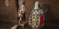 Two ‘ghosts’ pose in front of their ancestors’ house. <br>Porto-Novo, Benin. The Egungun association is a secret voodoo society that honours the spirits of their ancestors and perpetuates their memories. These ancestral spirits are believed to be in constant watch over their living relatives; they bless, protect and warn them, but can also punish them depending on whether they remember or neglect them. The spirits can also protect a community against evil spirits, epidemics, witchcraft and evil doers, ensuring their well-being, and may even be invited to come to earth physically. When they do, the Egungun are the receptacles of these spirits, appearing in the streets day or night, leaping, dancing or walking, and uttering loud cries. The spirit is supposed to have returned from the land of the dead to ascertain what is going on, so can be considered a kind of supernatural inquisitor who appears from time to time to inquire into the general domestic conduct of people and punish misdeeds. © Jean-Claude Moschetti, France, Finalist, Professional competition, Portraiture, Sony World Photography Awards 2023