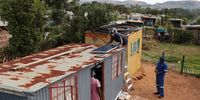 Technicians install a solar panel on the roof of a shack in the informal settlement of Melusi. (Photo: Felix Dlangamandla)