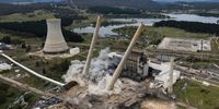 LITHGOW, AUSTRALIA - NOVEMBER 24: In this aerial view a controlled blast demolishes part of the old Wallerawang Powerstation on November 24, 2021 in Lithgow, Australia. Two large chimney stacks at Wallerawang Power Station were demolished by controlled blast this morning. The demolition is part of plans by to rejuvenate the decommissioned power station into a multi-use area. The Wallerawang Power Station was closed in 2014, with the site acquired by Greenspot in 2020, which plans to develop a large grid-scale battery on the old power station site. (Photo by Brook Mitchell/Getty Images)
