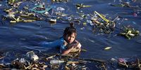 A Filipino teen wades along the Pasig river in Manila, Philippines, 15 June 2021. According to a report published in the Science Advances journal, rivers in the Philippines contribute tons of plastic waste which are funneled through Manila Bay to the world's oceans annually.  EPA-EFE/FRANCIS R. MALASIG