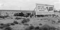 Photograph by Dorothea Lange during the Great Depression. Three families camped on the plains along the U.S. 99 in California. They are camped behind a billboard which serves as a partial windbreak. All are in need of work. 1938. The billboard says: ‘Next time try the train. Southern Pacific. Travel while you sleep’. Image: Library of Congress