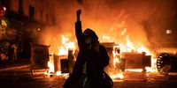 SEATTLE, WA - JUNE 08: A demonstrator raises their fist as a fire burns in the street after clashes with law enforcement near the Seattle Police Departments East Precinct shortly after midnight on June 8, 2020 in Seattle, Washington. Earlier in the evening, a suspect drove into the crowd of protesters and shot one person, which happened after a day of peaceful protests across the city. Later, police and protesters clashed violently during ongoing Black Lives Matter demonstrations following the death of George Floyd. (Photo by David Ryder/Getty Images)