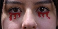 BOGOTA, COLOMBIA - MAY 19: A protester with tears of blood painted on her face poses for a photo while marching on May 19, 2021 in Bogota, Colombia. Colombians continue to take the streets after three weeks to demonstrate against Ivan Duque's administration. Even after the withdrawal of a controversial tax reform, demands turned into a widespread expression of anger over poverty, inequality and police brutality. As protesters claim for the end of violent crackdown, President Duque ordered maximum deployment of armed forces to clear blockades. (Photo by Guillermo Legaria/Getty Images)